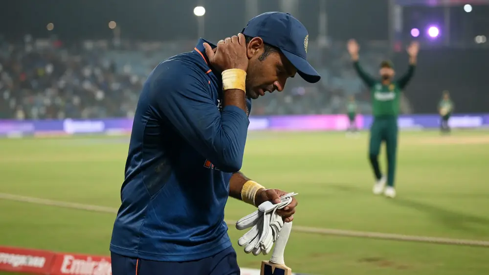 Cricket batter mid-shot under floodlights with a blurred outfield and crowd behind the ropes