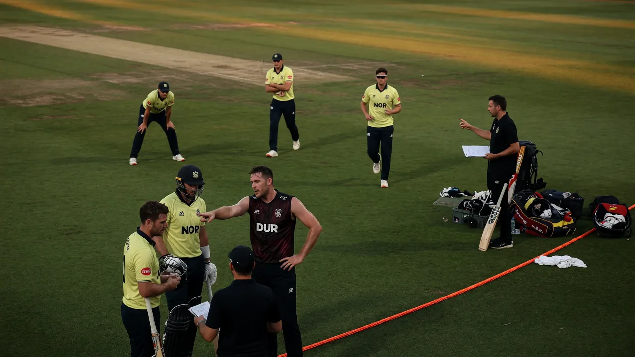 Fielders gather in a tight ring as a fast bowler runs in during a county T20 match under floodlights